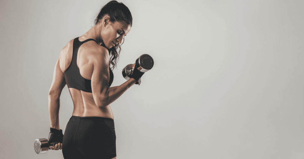 A strong woman lifting dumbbells, showcasing muscular definition and focus, symbolizing personal trainers' ability to specialize in different fitness areas.