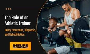 Athletic trainer assisting a focused athlete with weightlifting, representing the crucial role in sports medicine, as explained in 'What is an Athletic Trainer' article by INSURE FITNESS GROUP.