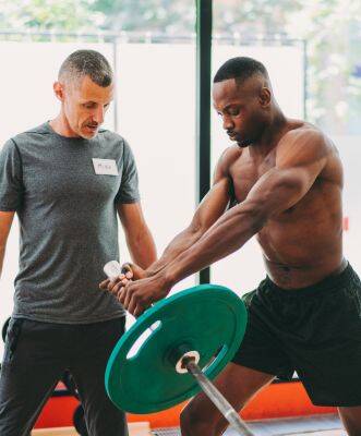 A trainer engaging in exercise while discussing fitness trainer insurance with his client